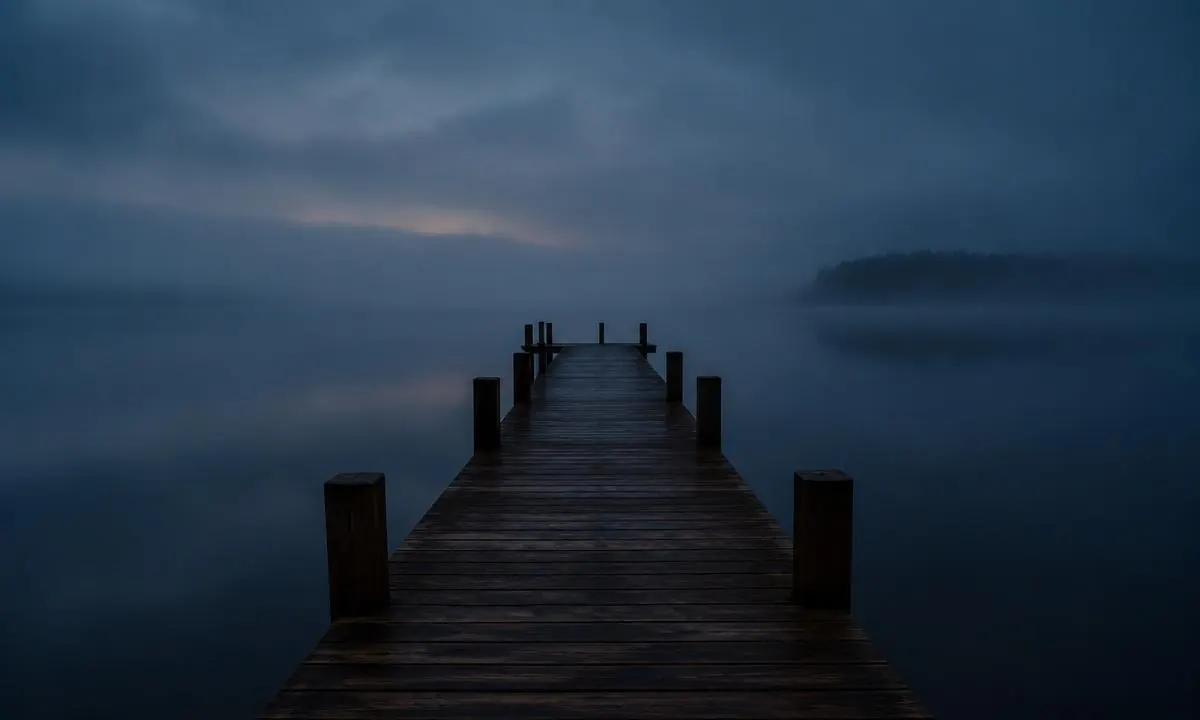 Holzsteg, der in der blauen Dämmerung auf einen nebeligen See hinausführt